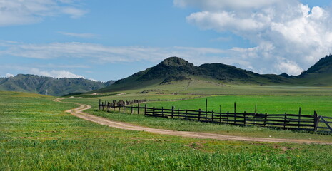 Russia. The South of Western Siberia, the Altai Mountains. A dirt road stretching into the distance along a wooden fence around summer pastures. © Александр Катаржин