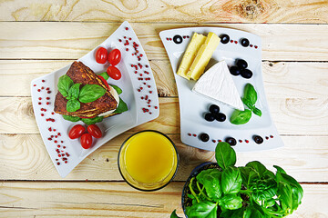 Sandwich with cheese and tomato with orange juice on a wooden background — flat lay