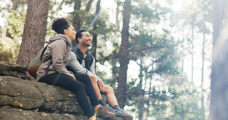 Nature, hiking and a couple relax on adventure trail in forest and sitting on a rock. Health, happy...