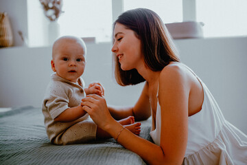 young mom playing with baby on the bed