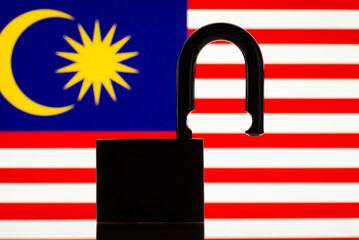 Reopen Malaysia, tourism, open borders concept. Flag of Malaysia with open lock on the foreground