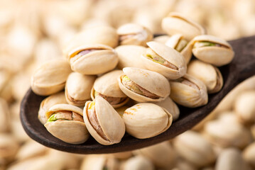 Pistachio in dark wooden spoon. Many taste pistachios with salt ready to be eaten