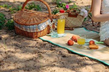 Summer picnic on beach by sea. Fresh fruits, juice, cookies and peaches near picnic basket on cloth. High quality photo