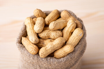 Peanuts in bag on wooden table. Close up of peanuts in small linen bag