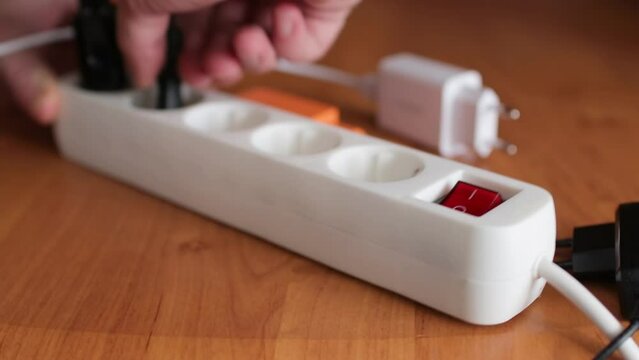 Hands turn off and unplug wires from electricity switch at home. Energy saving concept