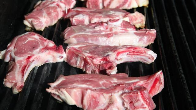 Raw lamb chops on a grill of a gas barbecue, Grilling lamb chops outdoors, Grilled raw Lamb chops, Outdoor BBQ cooking, Gas Barbecue Grill