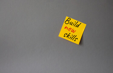 Build New skills symbol. Concept word Build New skills on orange steaky note. Beautiful grey background. Business and Build New skills concept. Copy space