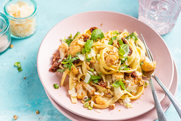 Tagliatelle pasta dish with cauliflower, sun dried tomatoes, basil, chiev, walnuts and parmesan cheese