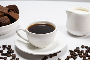 Coffee with milk - a cup of coffee and a milk jug on a white background, a place for text, a delicious breakfast.