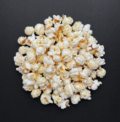 Handful of popcorn on black background. Copy space, top view, close-up.