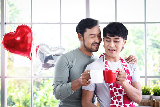 Happy smiling LGBT couple sharing special moment together on Valentine Day, Asian gay male lover drinking hot beverage coffee at kitchen, celebrate memorable anniversary unforgettable romantic dating