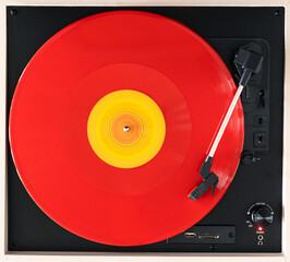 A red with yellow vinyl record spinning on a turntable