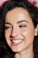 Portrait of smiling woman with freckles looking away isolated on pink.