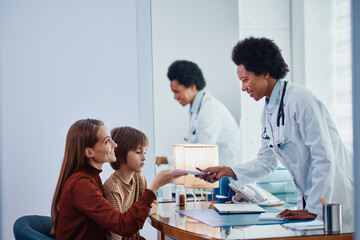 Happy mother takes prescription for her small son form African American pediatrician at medical clinic.