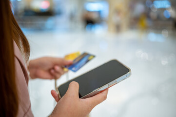 Young Asian woman using credit card and mobile phone for online shopping , technology money wallet and online payment concept, credit card mockup