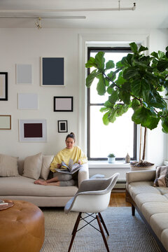 Woman reading magazine while sitting on sofa at home