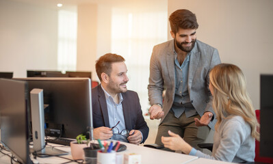 Obraz premium Three 30s colleagues using laptop discussing online presentation, prepare collaborative on-line project, make computer task, share ideas consider strategy, develop start up, plan work sit at workplace