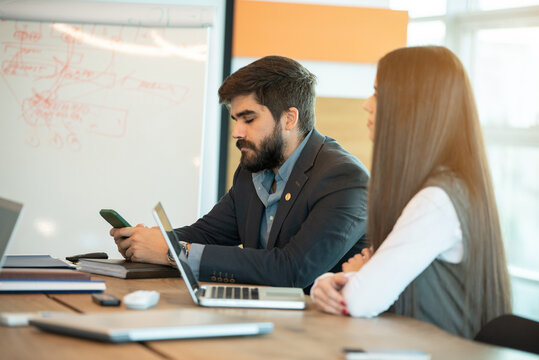 Bored businessman using phone during a meeting in office - Powered by Adobe