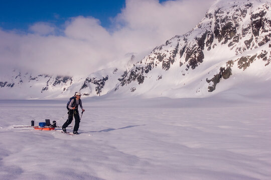 Glacier geology PhD student skis over the Brady Glacier, while pulling a sled of geophysical equipment.