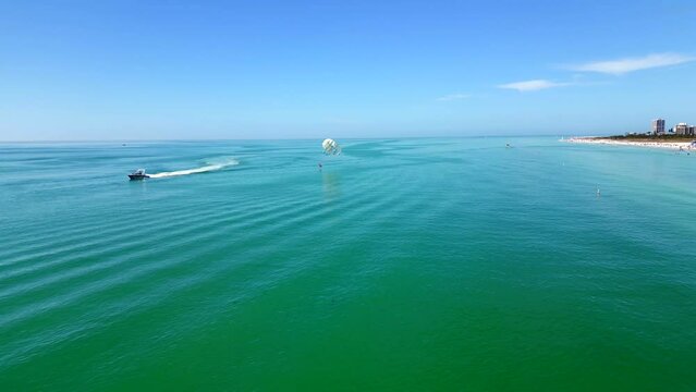 Aerial video parasail dipping feet in ocean tourist watersports