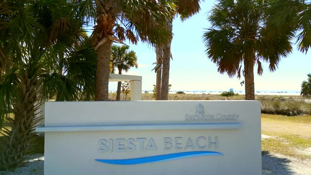 Aerial flyover Sarasota Beach sign on Siesta Key to reveal dunes and beach 4k