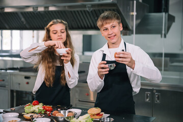 Two student boy and girl enjoy studying cooking class at school kitchen.