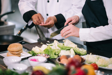 Caucasian schoolgirl holding vegetable basket in cooking classroom, Senior chef teaching to select...