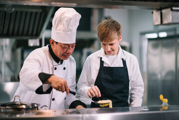 Mature asian teacher teaching schoolboy chef students to select ingredient for cooking in class.