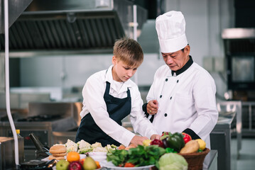 Mature asian teacher teaching schoolboy chef students to select ingredient for cooking in class.