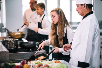 Group of diverse student chef learning cooking class in the kitchen. Mature asian teacher teaching...