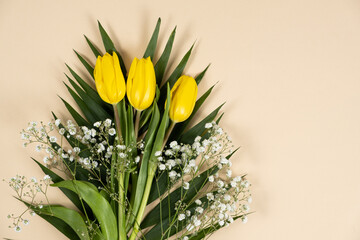 Bouquet of flowers of tulips and gypsophila on a beige background, hello spring, from March 8