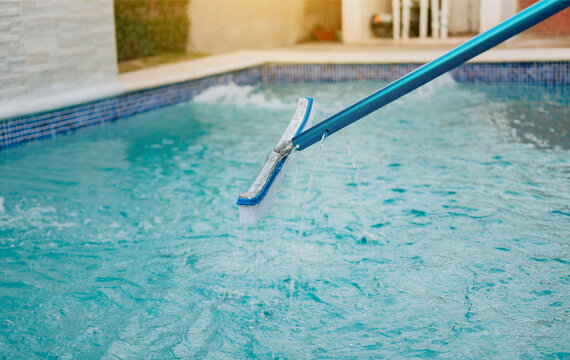 Swimming pool cleaning with brush. Pool brush for wall cleaning, Worker cleaning a pool with special brush