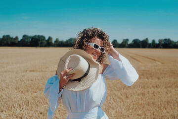 portrait of smiling young woman in white sunglasses posing outdoors in a beautiful dress