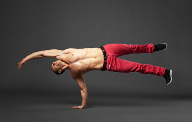 Young male professional dancer B-boying in studio isolated on gray.