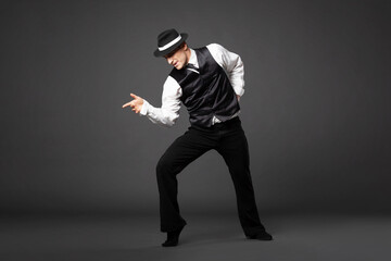 Confident young man dancing in gangster style suite.