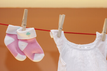 Medias rosadas de bebe colgada con ganchos de madera y ganchitos en forma de flor color beige