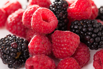 handful of raspberry and blackberry berries on white background