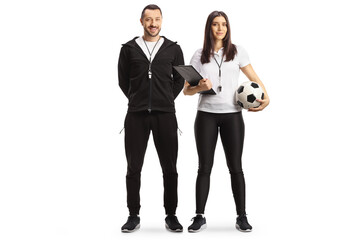 Full length portrait of a male and female football coaches posing - obrazy, fototapety, plakaty