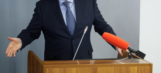 Man - lawyer, politician, businessman or teacher speaks in front of microphones, gesturing and...