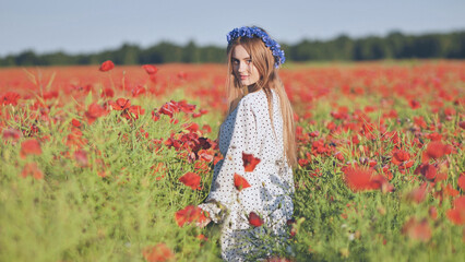 Ukrainian girl walking through a red poppy field.