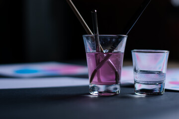 Watercolor paintbrushes in a glass of water. Artistic concept on a dark background.
