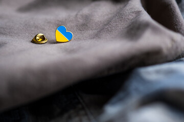 Metal badge with the flag of Ukraine in the shape of a heart on military jacket. Support for...