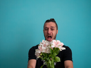 White Man Terrified by Holding Flowers on a Turquoise Background