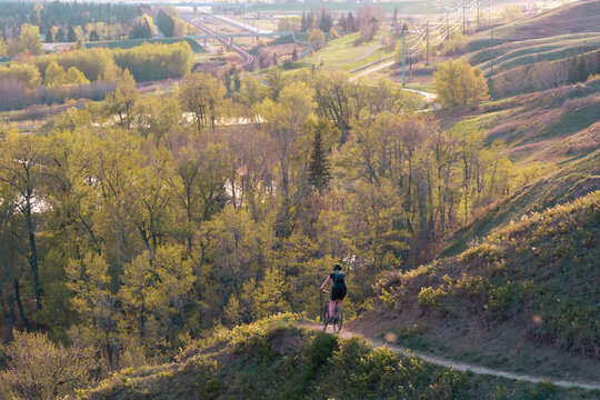 Cyclist riding a mountain bike through Bowmont Park in Calgary on a summer afternoon