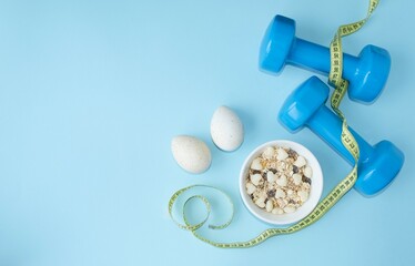 Sports lifestyle, balanced diet.  On a blue background, blue dumbbells, a centimeter, diet food, proteins, carbohydrates.  The concept of diet, proper nutrition.