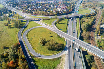 Fototapeta premium Highway multilevel crossing. Spaghetti junction on A4 international highway with Zakopianska multilane street and railway. A part of freeway around Krakow, Poland. Aerial view from above
