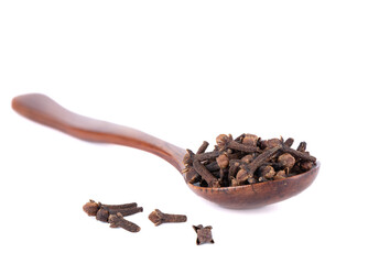 Selective focus on clove seasoning on wooden spoon and white background.