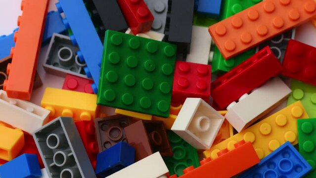Multi-colored toys made of plastic cubes and bricks revolving on a turntable, children's constructor.The concept of the development of logic, children's creativity.Macro plan constructor, background.