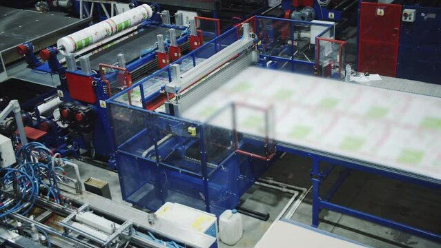 Professional machinery equipment for plastic materials production in workshop. Operating conveyor moves polycarbonate sheets on belt at factory