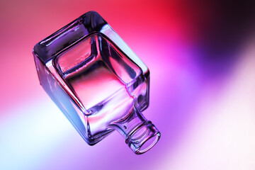 Bottiglietta in vetro trasparente, isolata, in controluce su fondo colorato